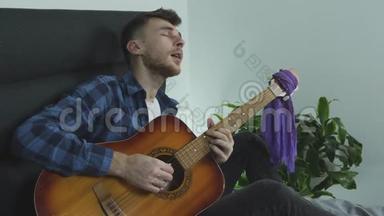 吉他音乐家用吉他演奏民谣歌曲，并在家里床上有感情地唱歌。